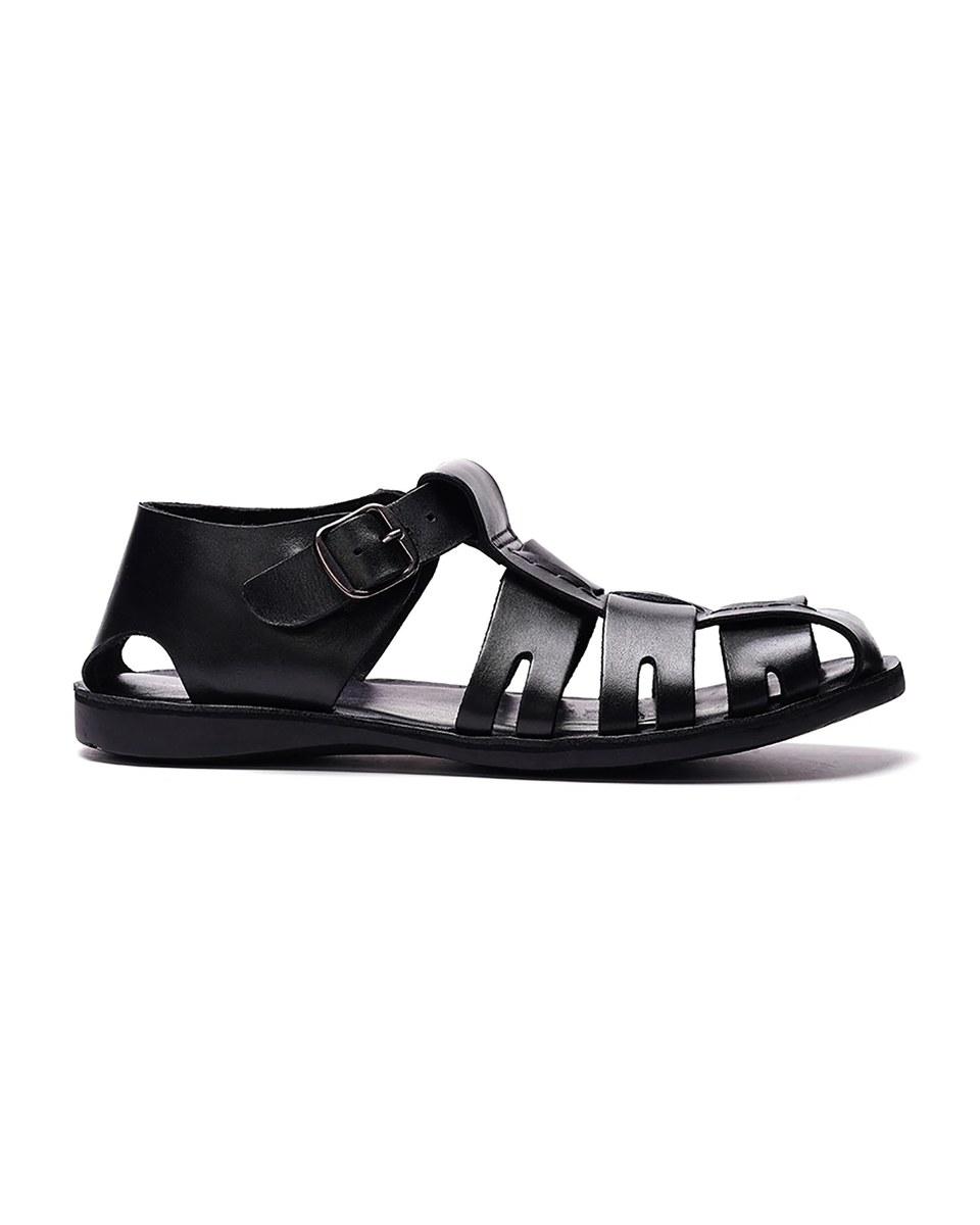 The Santorini Fisherman Sandal in black leather, seen from the side: woven straps over the toes and a buckled strap at the ankle.