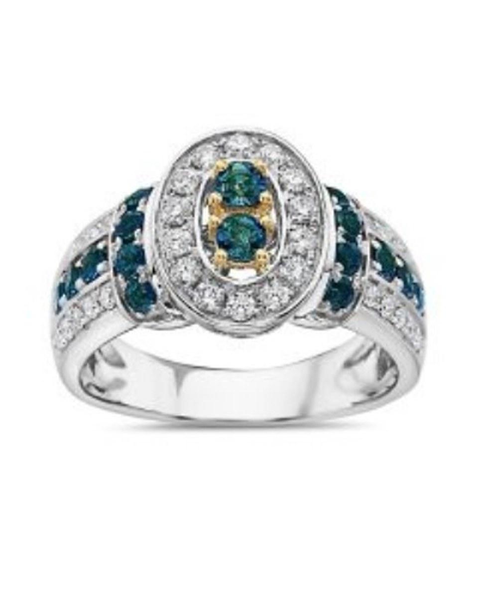 The TruAmore Opulent EXOTIC Oceanic Ring: an oval of teal stones set in gold, ringed with small clear stones, with more teal stones down each shoulder of a white-metal band.